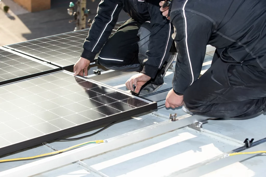 Zwei Männer befestigen Solarpaneele auf einem Dach